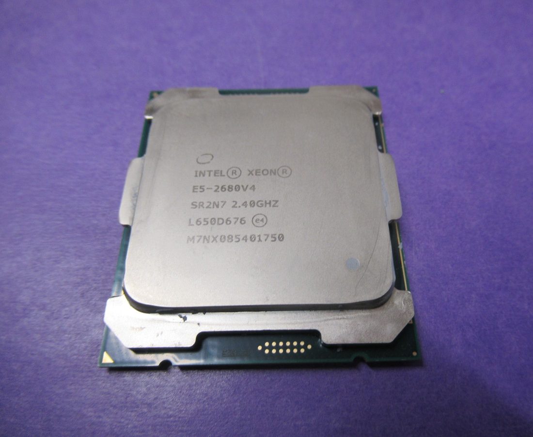 Intel Xeon E5-2680 v4 processor, top face, laser-etched markings - photographed on a plain surface